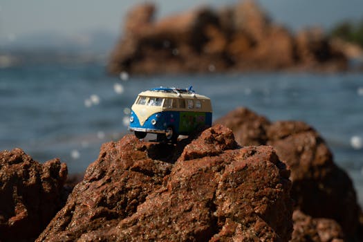 A toy Volkswagen van placed on eroded rocks by the sea, capturing a playful outdoor adventure scene.