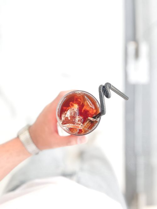 Free Top view of a refreshing iced tea with a straw in a glass, held by a person. Stock Photo