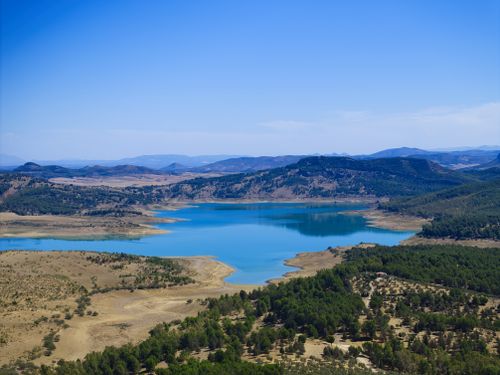 Free Captivating aerial view of Teba, Spain's serene lake surrounded by rolling hills and trees. Stock Photo