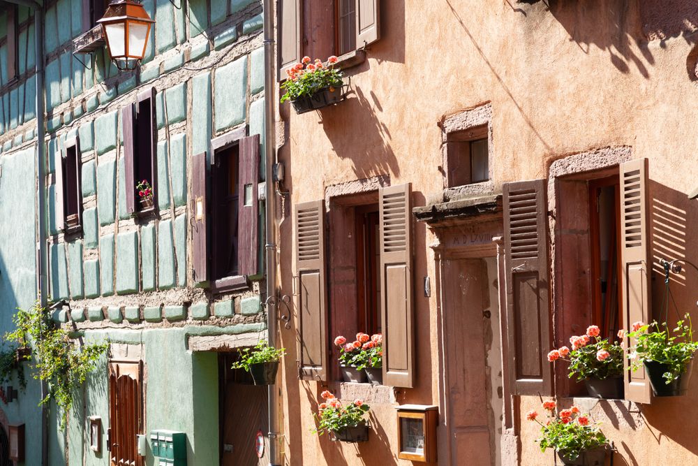 Case colorate din lemn cu ghivece de flori pe strada principală din Riquewihr, Alsacia