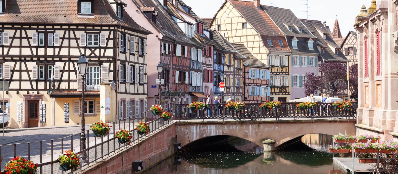Scenic view of Colmar's half-timbered houses and picturesque bridge over a peaceful canal.