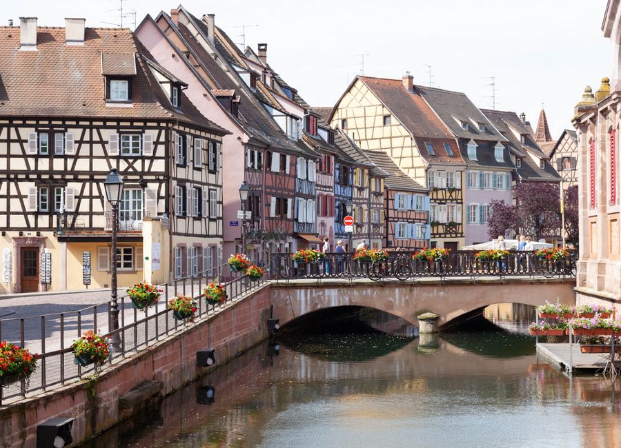 Scenic view of Colmar's half-timbered houses and picturesque bridge over a peaceful canal.