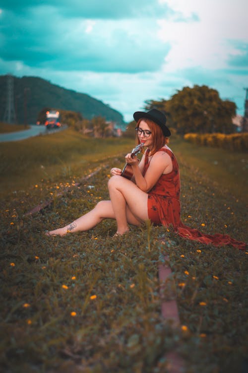 Woman Sitting on Ground Playing Guitar
