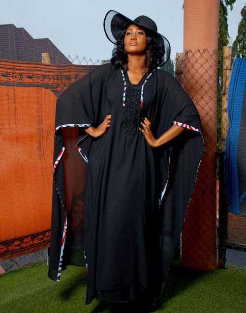 Free A beautiful woman poses elegantly in a long black dress and hat, showcasing fashion outdoors. Stock Photo