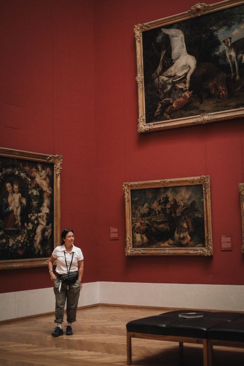 Free A woman standing in an art museum in Munich, Germany, observing classical paintings on the wall. Stock Photo