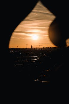Scenic view of Munich's urban skyline silhouetted against a vibrant sunset.