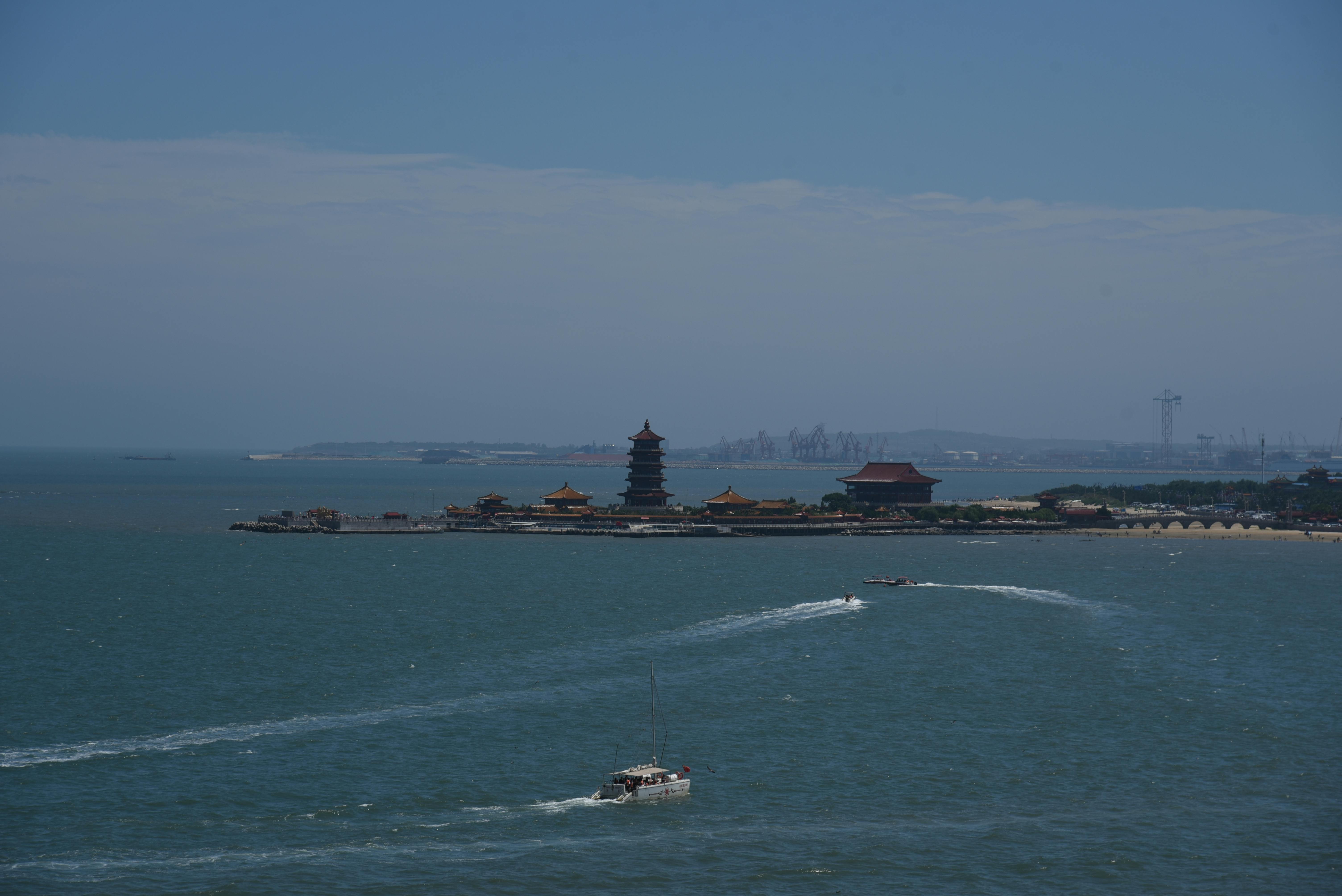 Scenic aerial shot of a coastal pagoda and boats in China on a sunny day.