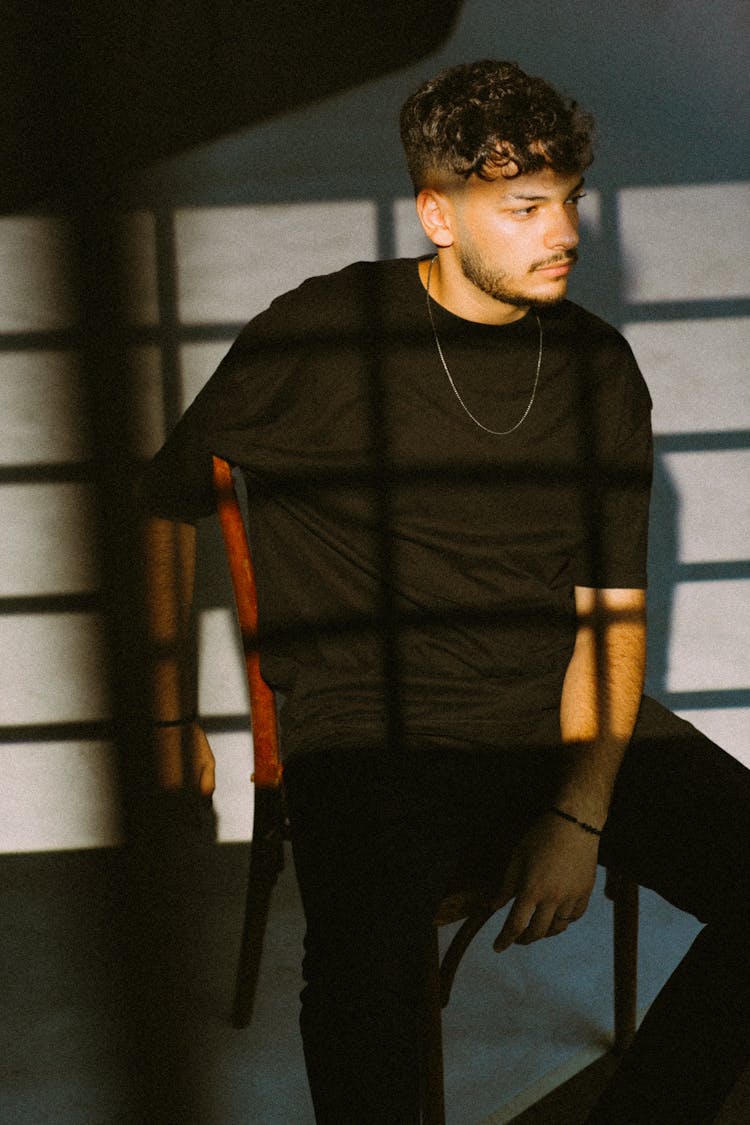 Young Brunette Man In Black T-Shirt Sitting On A Chair