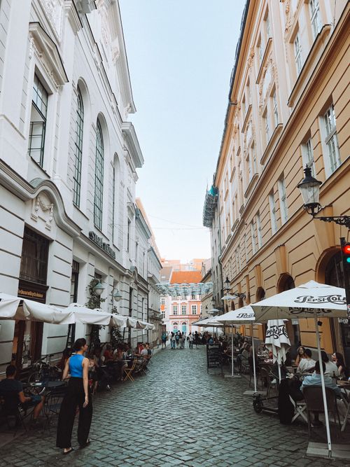 Free Quaint cobblestone street in an old town with cafes and pedestrians on a sunny day. Stock Photo