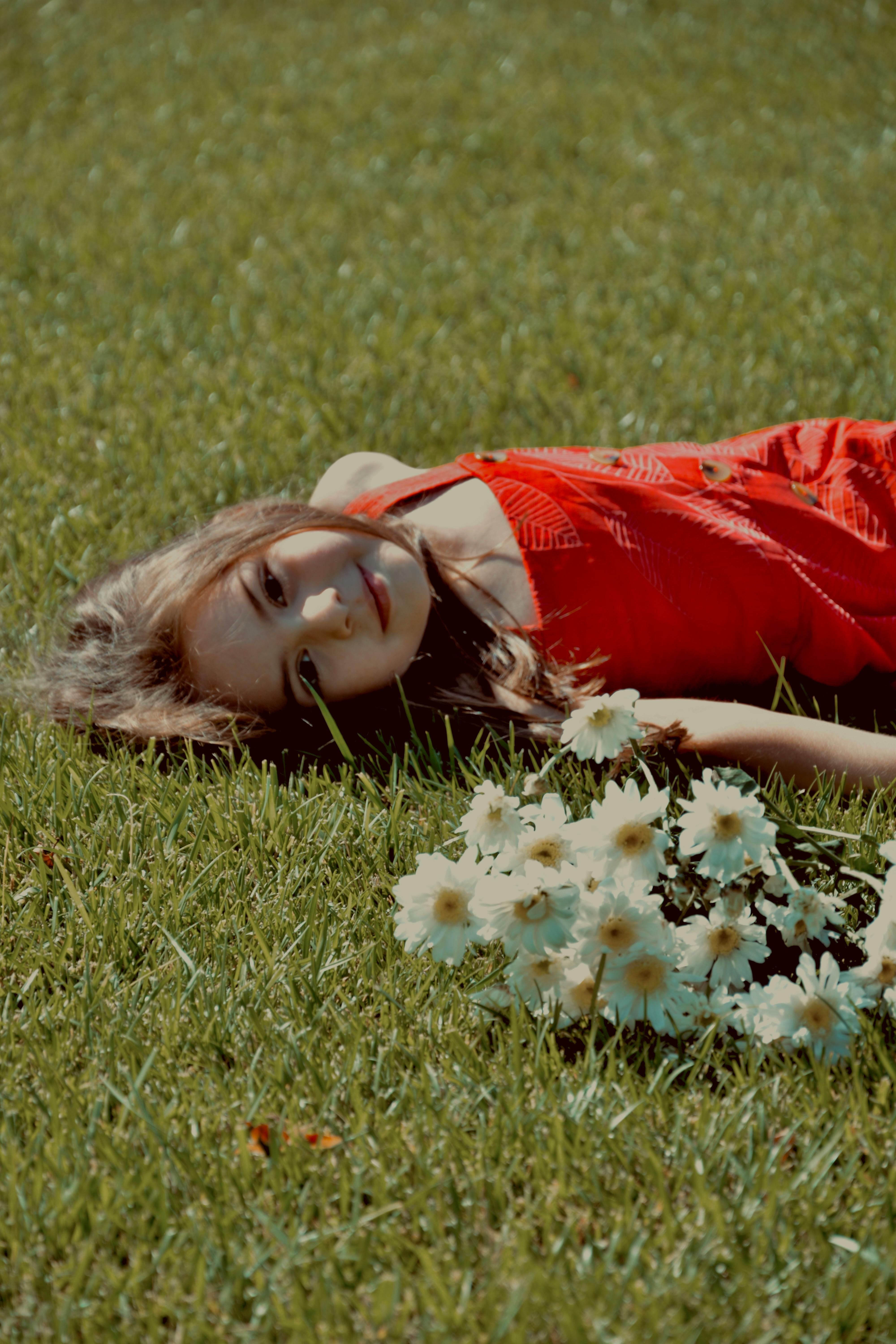 Girl in Red Dress Lying Down on Grass with Flowers · Free Stock Photo