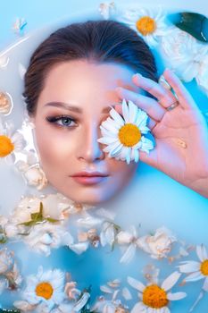 A serene woman in a milk bath adorned with chamomile flowers, evoking calmness.