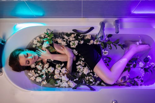 Woman in Bath Filled With White Roses