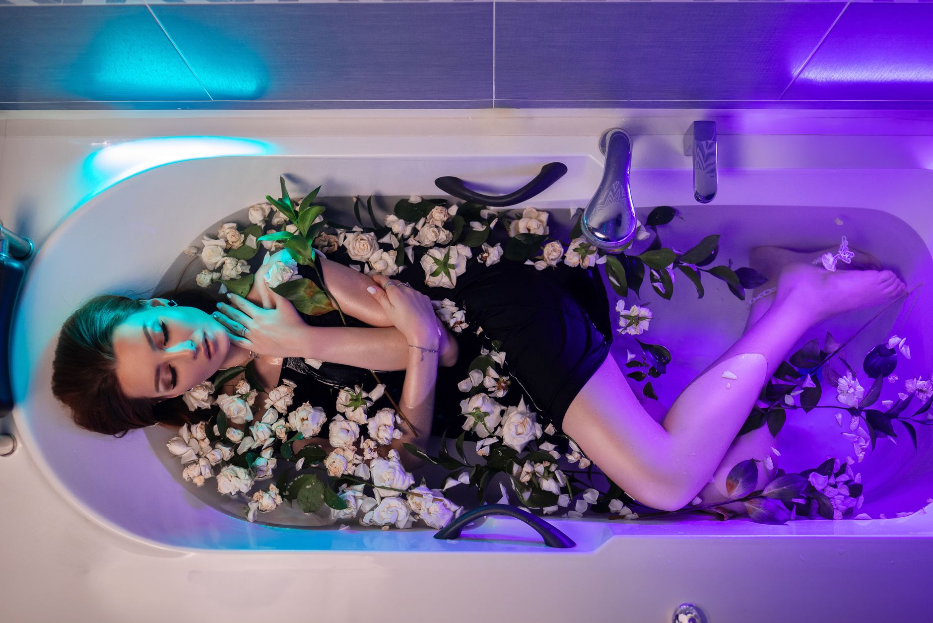 Woman soaking in a bathtub filled with white roses, creating a tranquil and aesthetic mood.