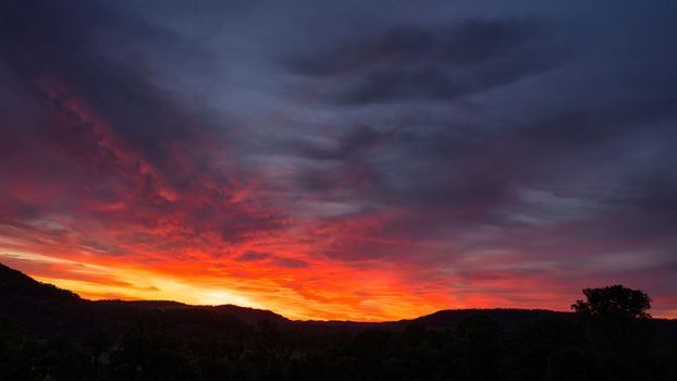 Stunning sunset with vivid colors and silhouetted hills, capturing nature's beauty.