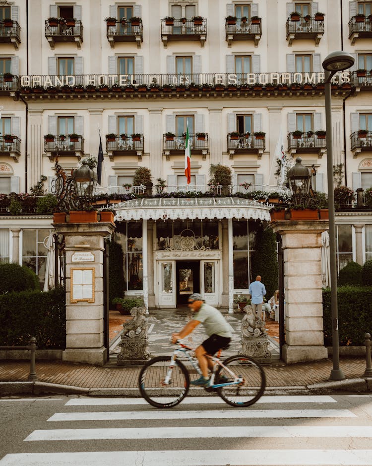 Man Cycling Near Grand Hotel Des Iles Borromee In Italy