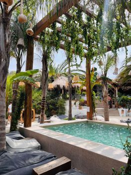 Luxurious outdoor pool surrounded by tropical plants and wooden pergola for a relaxing paradise feel.