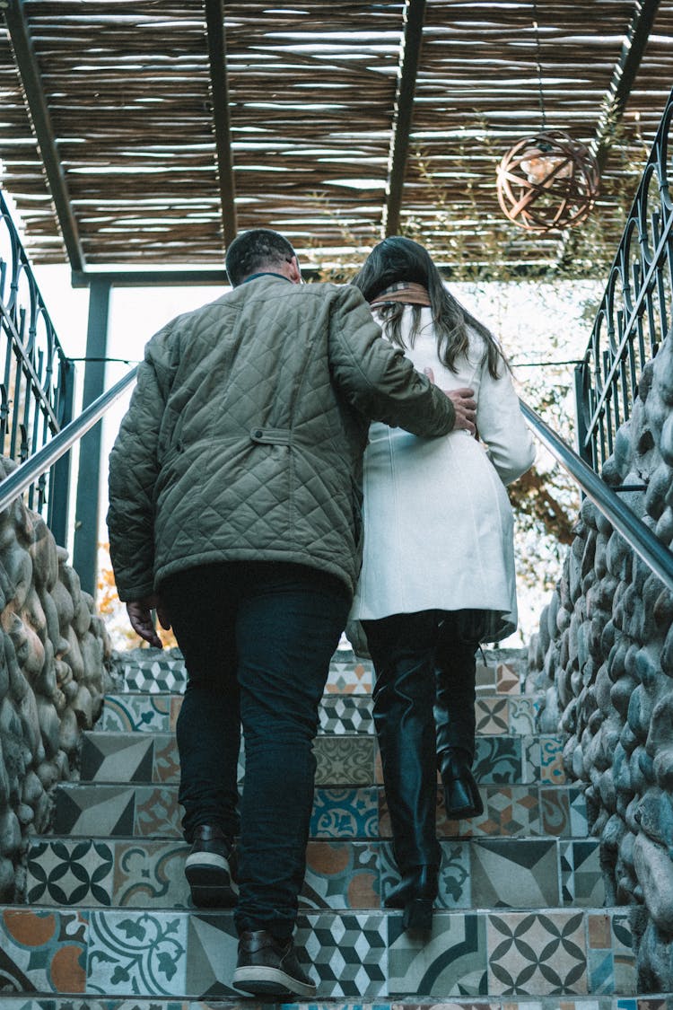 Woman And Man Walking Upstairs On Decorated Stairs