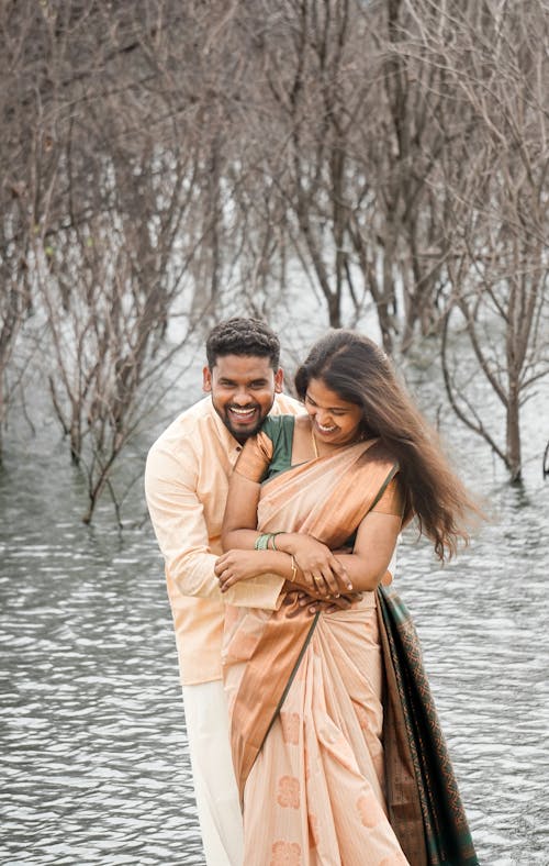 Smiling Couple in Traditional Clothing Hugging by Water