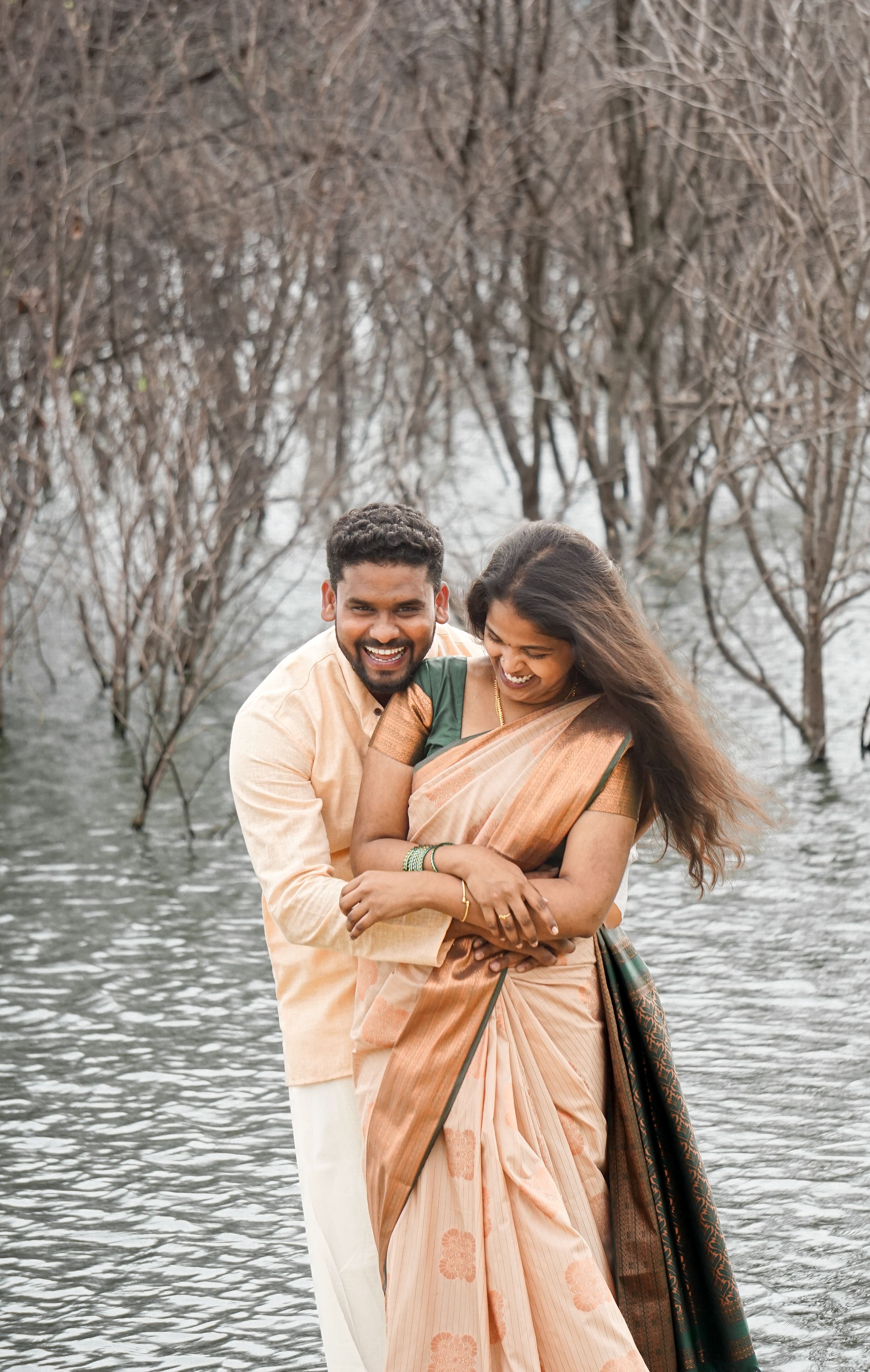 Smiling Couple in Traditional Clothing Hugging by Water · Free Stock Photo