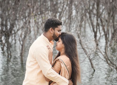 Free A loving couple embraces by a serene water backdrop in traditional clothing. Stock Photo
