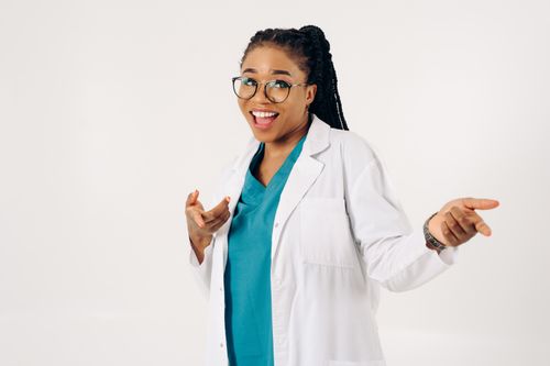 Free Smiling female doctor pointing in a cheerful pose on a white background. Stock Photo