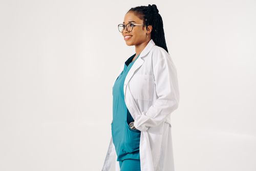 Free Smiling female doctor in uniform and eyeglasses standing against a white background. Stock Photo