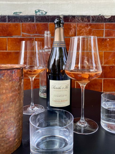 Elegant display of champagne bottle and glasses on a black table against rustic bricks, perfect for celebratory occasions.