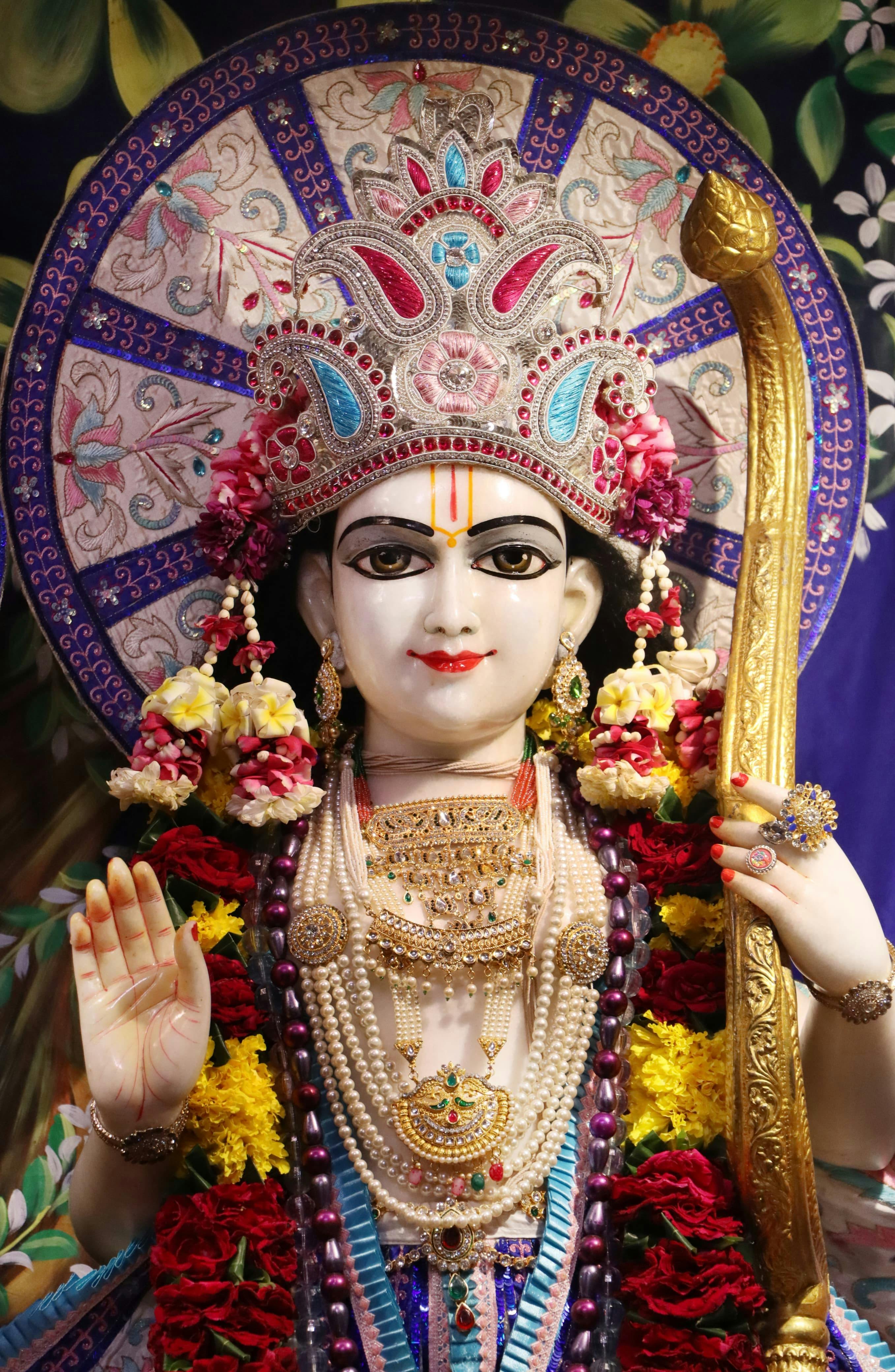 Vibrant close-up of a Hindu deity statue adorned with colorful decorations and jewelry.