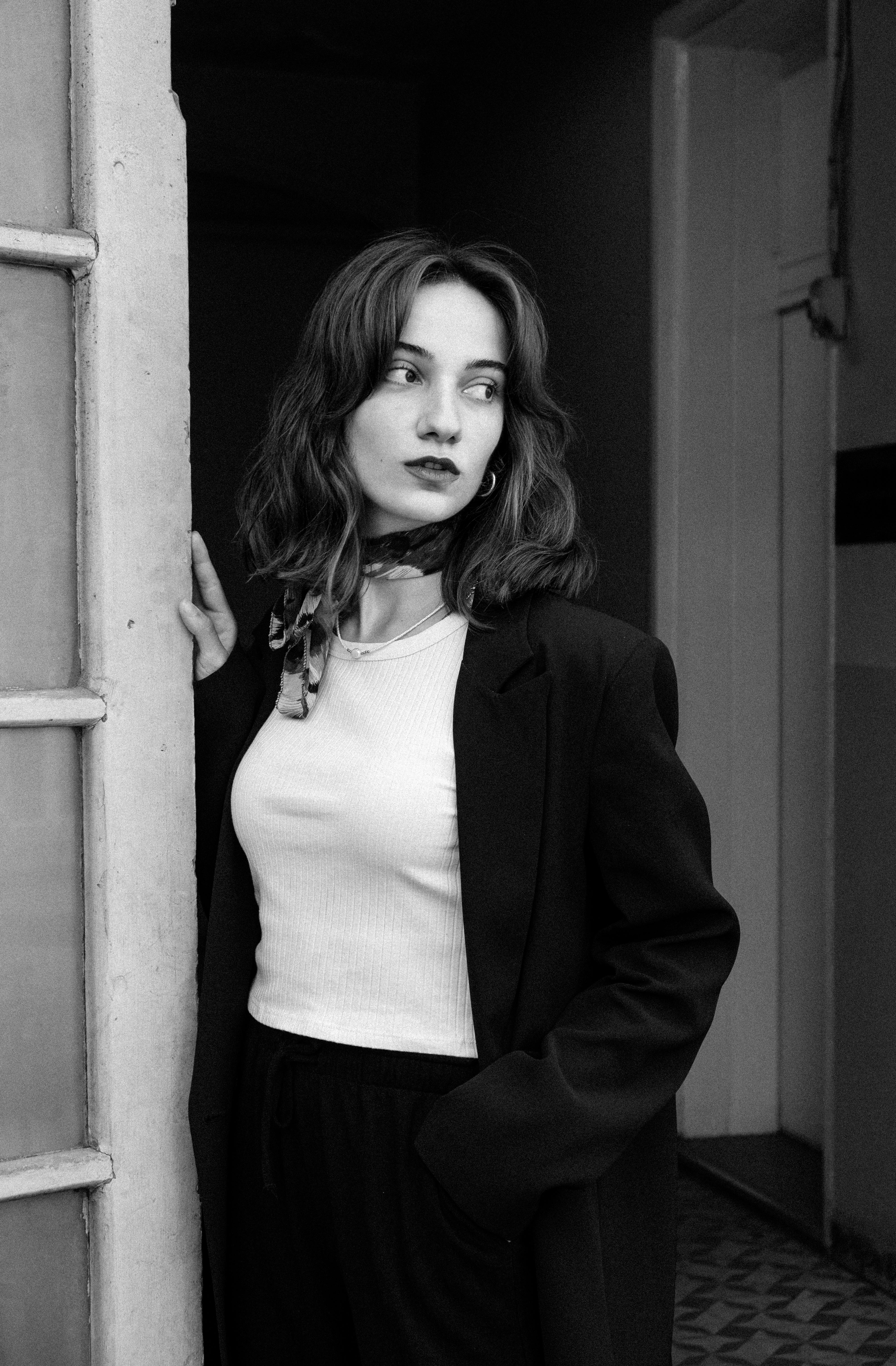Stylish woman in a black and white portrait wearing a blazer and neckerchief.