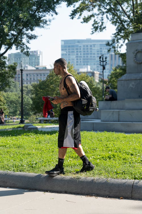 Topless Black Man with Tattoos Walking in City Park