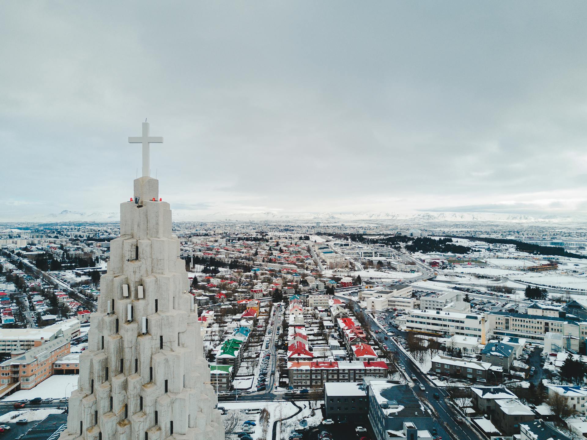 Aerial view of Reykjavik showcasing a church steeple and snow-covered urban landscape.