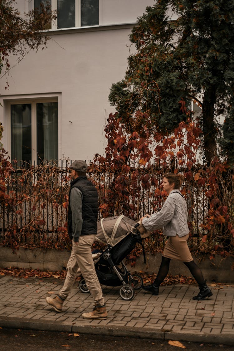 Couple With Stroller Walking On City Street