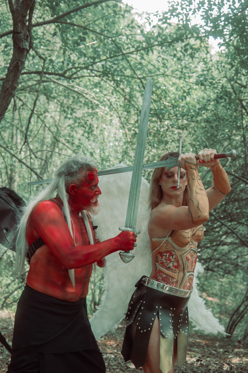 Free A dramatic outdoor fantasy scene depicting an angel and a devil battling in a forest. Stock Photo