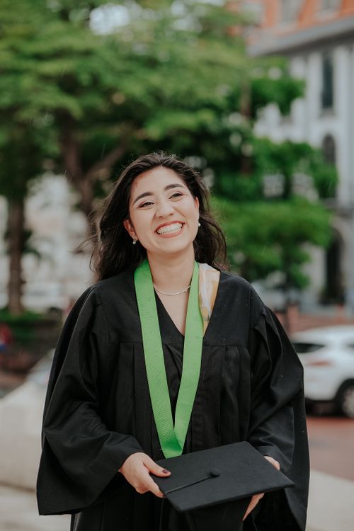 Free Joyful graduate woman smiling after ceremony, holding cap outdoors. Stock Photo