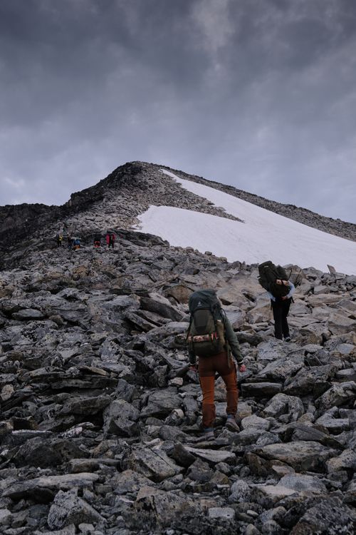 Free Group of hikers with backpacks climbing a rocky mountain in winter weather. Stock Photo