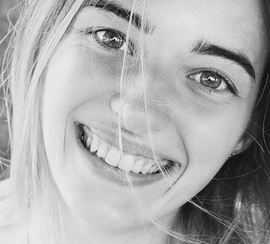 Black and white close-up portrait of a smiling young woman with a joyful expression.