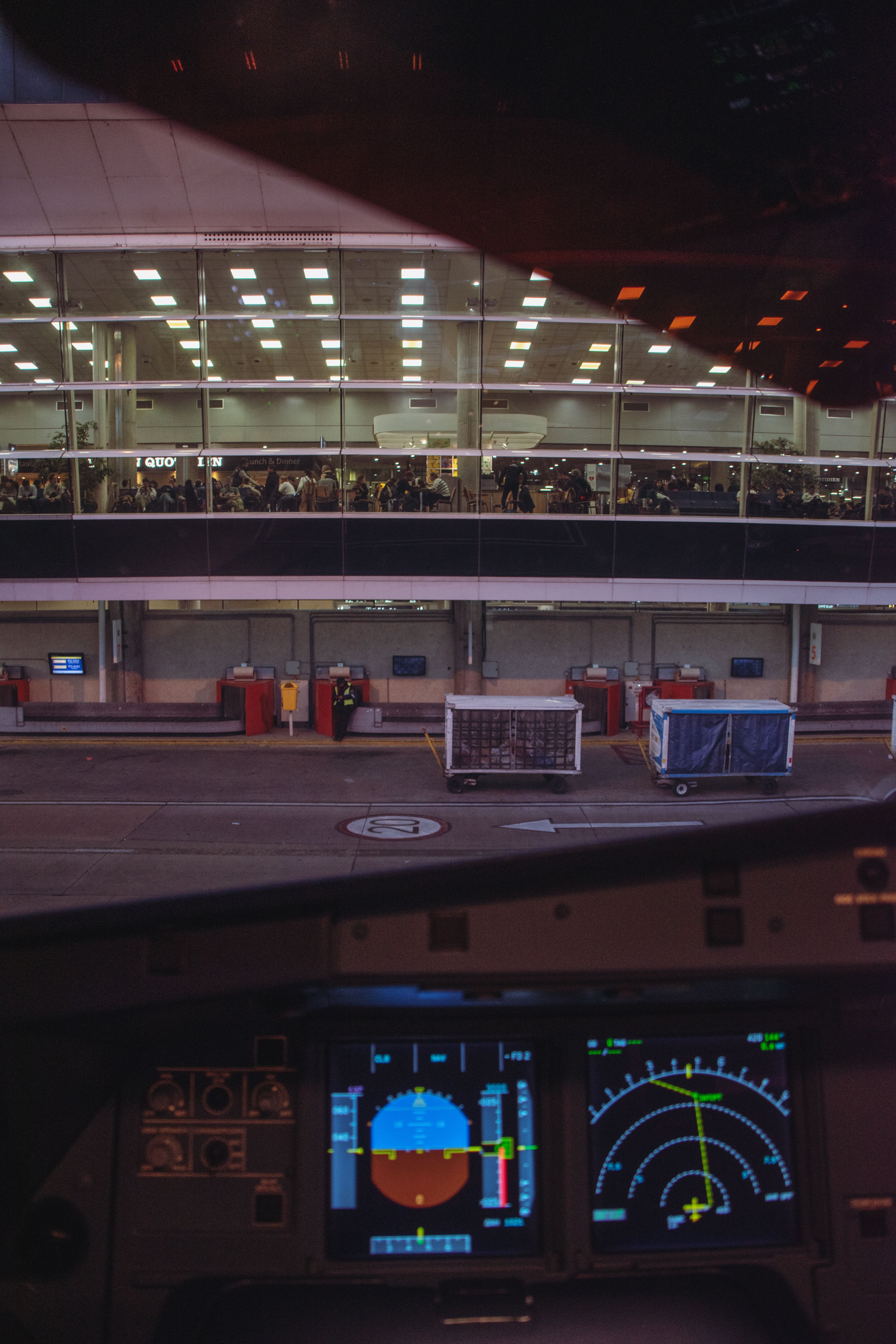 A dynamic view from an airplane cockpit showing a busy airport terminal and jetway.