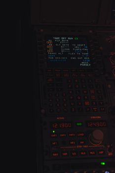 Close-up of an illuminated aircraft cockpit dashboard with control panels and displays, taken at night.
