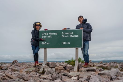 A couple poses at the Gros Morne summit, showcasing their hiking achievement in Canada.