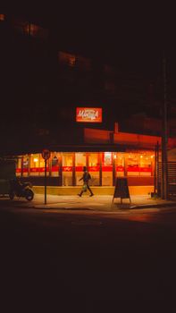 A man walking past a brightly lit shopfront in Viña del Mar, Chile, captured at night.