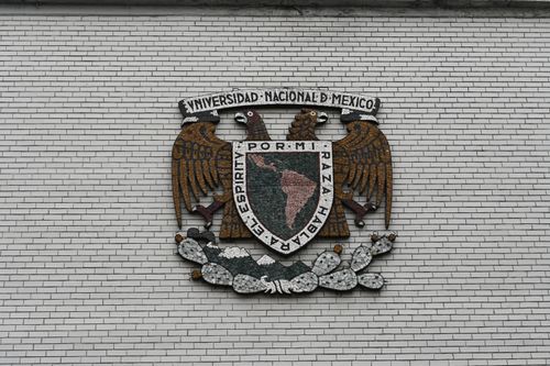 Free Close-up of the Universidad Nacional de Mexico crest on a white brick wall. Stock Photo