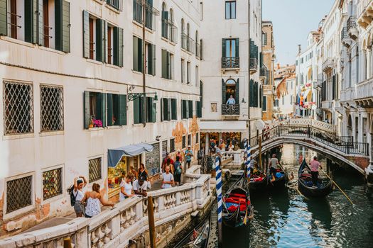 Charming Venice canal with gondolas and vibrant tourist activity, showcasing classic architecture.