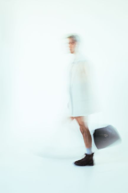 Artistic studio portrait with motion blur of a man in a white coat, conveying movement.