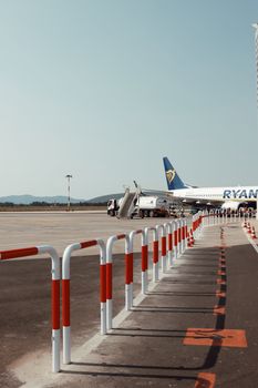 A Ryanair plane stationed on the tarmac at an airport in Sardegna, Italy, under a clear sky.