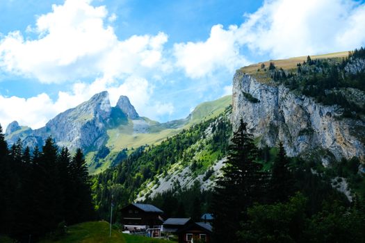 Scenic view of alpine chalets nestled among lush summer mountains and forests.