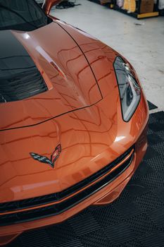 Close-up of an orange sports car in an indoor showroom, emphasizing luxury and design.