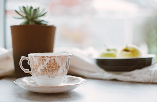 Free White and Brown Floral Ceramic Teacup on White Ceramic Saucer Near Brown Pot Stock Photo