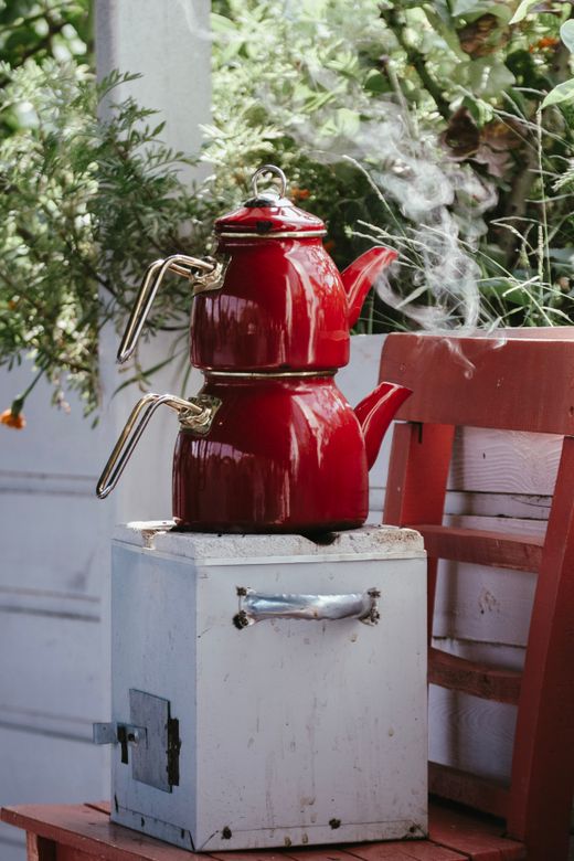 Red enamel stacked double tea kettle steaming on a white stove box