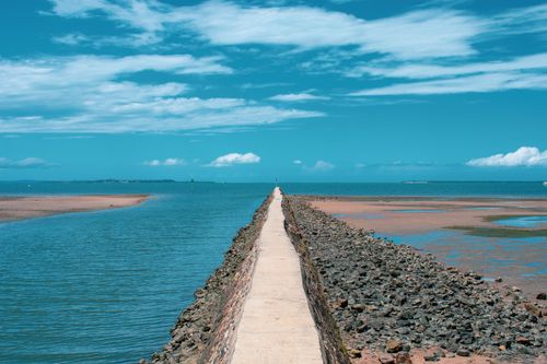 Free Stone pathway extending into the clear blue ocean under a bright sky. Stock Photo
