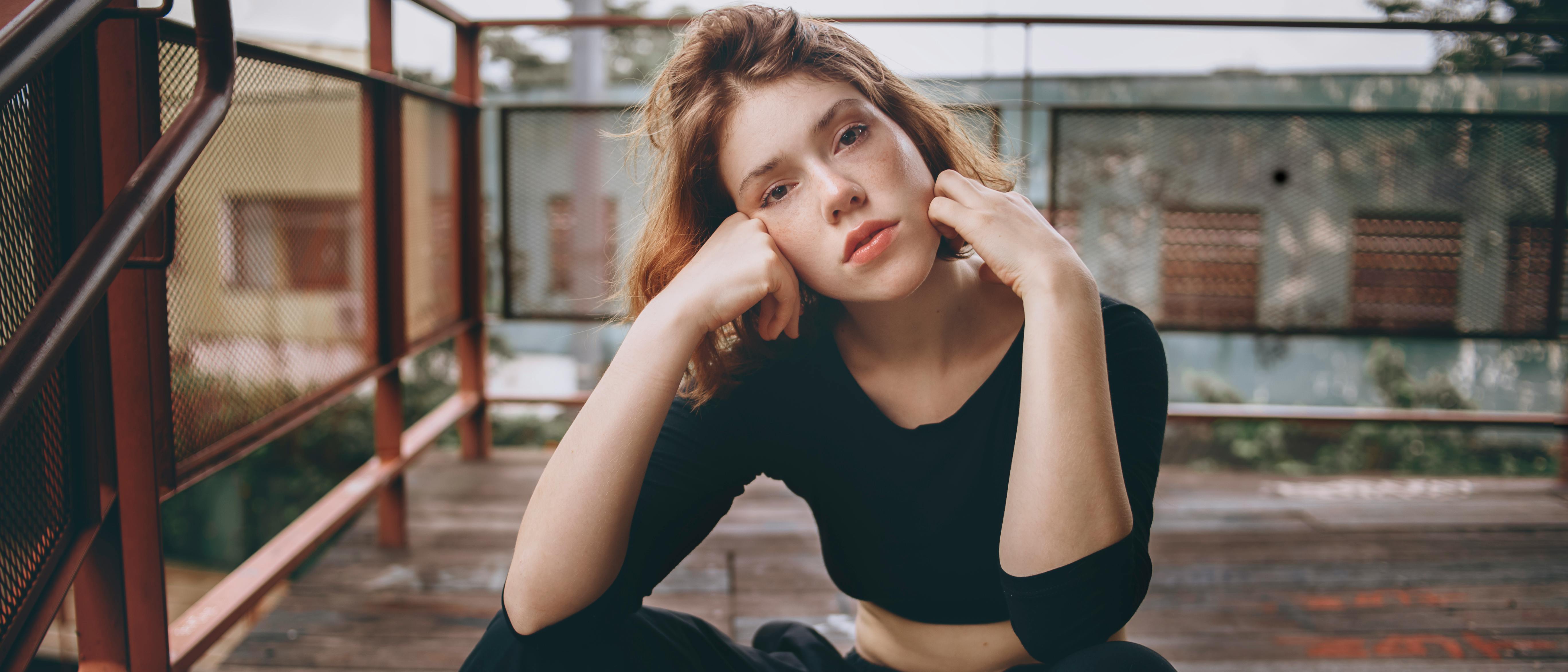 一位穿着休闲装的年轻女子，轻松地坐在户外